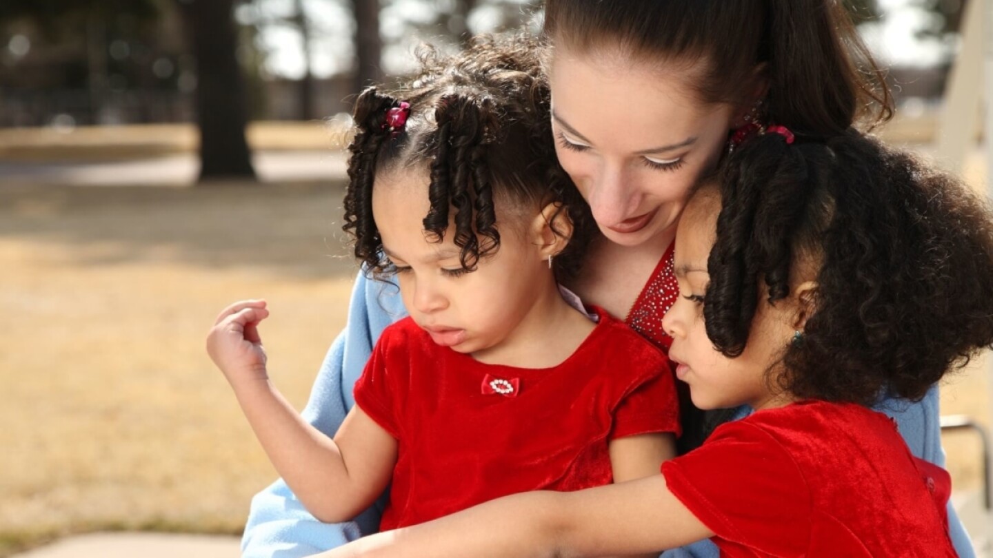A woman reads with two little girls