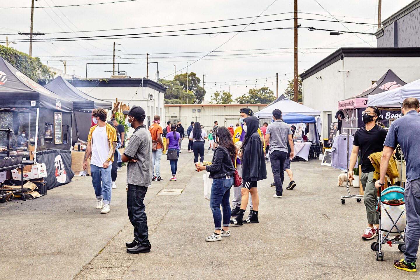Attendees peruse and wait in line in between booths and tents at the FilLed Market, an outdoor market filled with curated Filipino American food and goods.