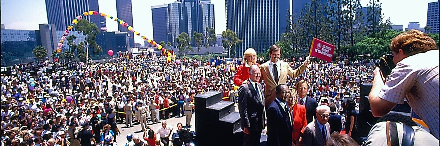 Mayor Tom Bradley and a group of noted Angelenos are photographed with a large crowd behind them during the 1984 Los Angeles Olympics.