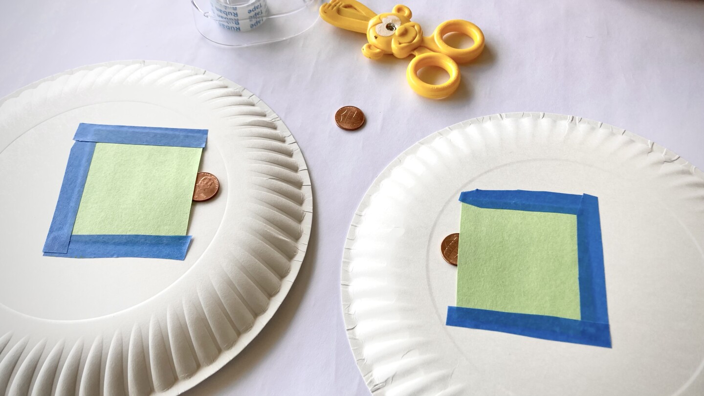 Two paper plates with small pockets made out of paper on the back hold a penny each.