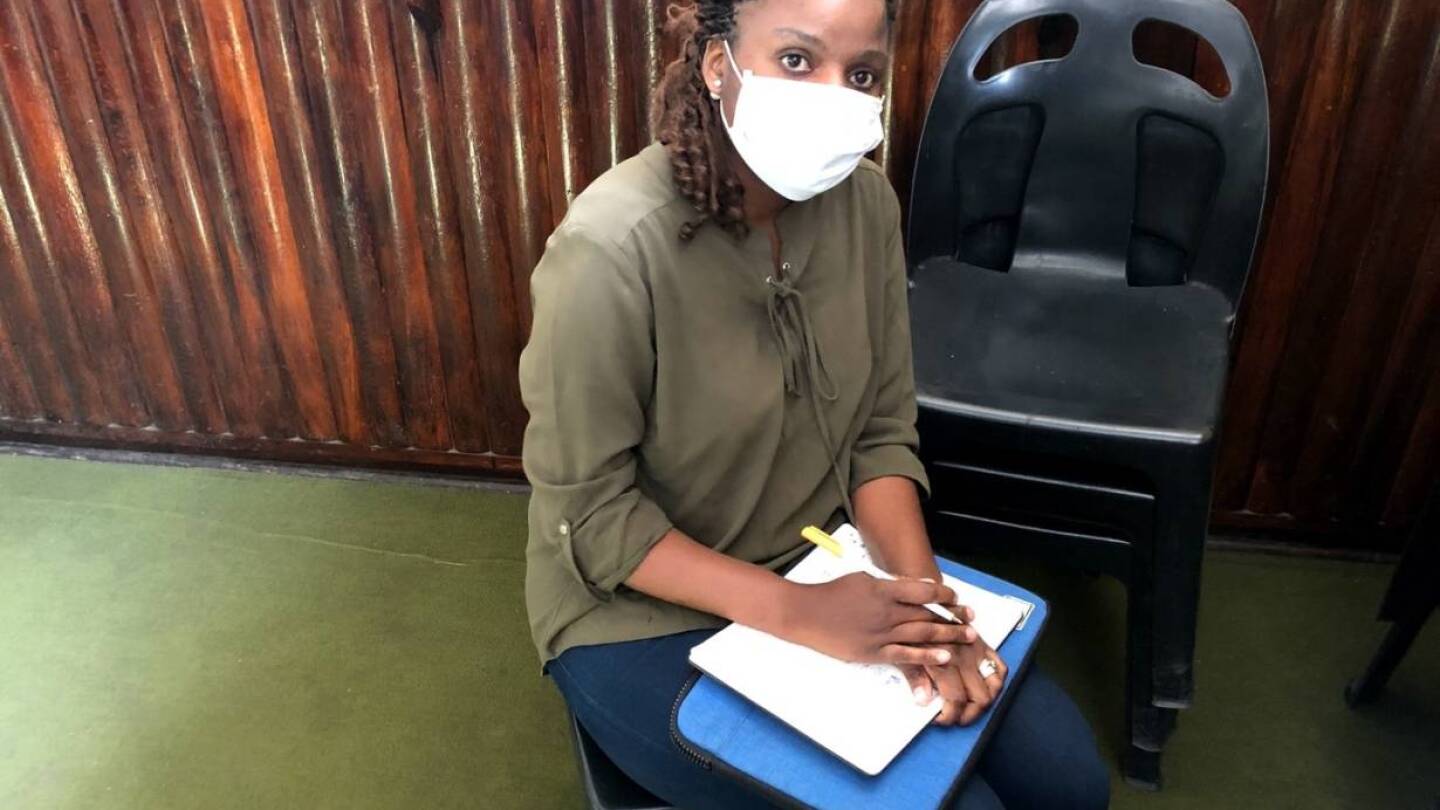 Sithandekile Mlauzi, 29, a VSO volunteer sits with her notebook and tablet on her lap in Bulawayo, Zimbabwe. 11 July 2020. | Thomson Reuters Foundation/Lungelo Ndlovu