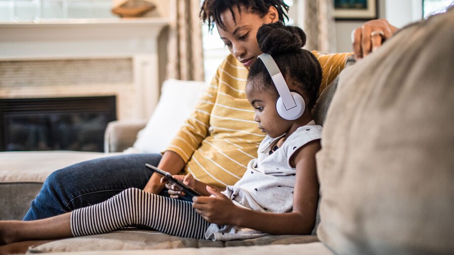Mother and daughter on couch using tablet
