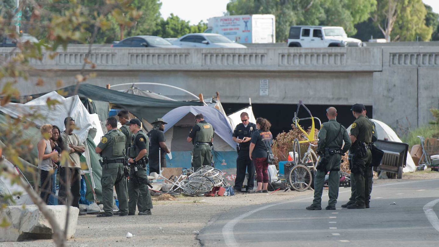 Orange County Sheriff’s Deputies question residents of the Santa Ana Riverbed homeless encampment