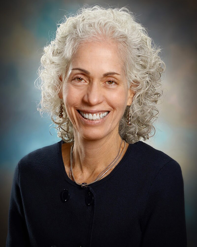 Barbara Ferrer smiles wearing a black top and her signature white curly hair.