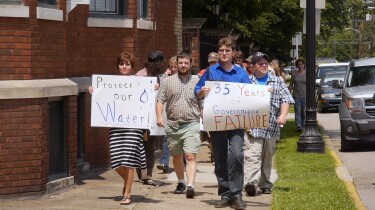 A group of demonstrators hold signs. | Still from Global Mosaic