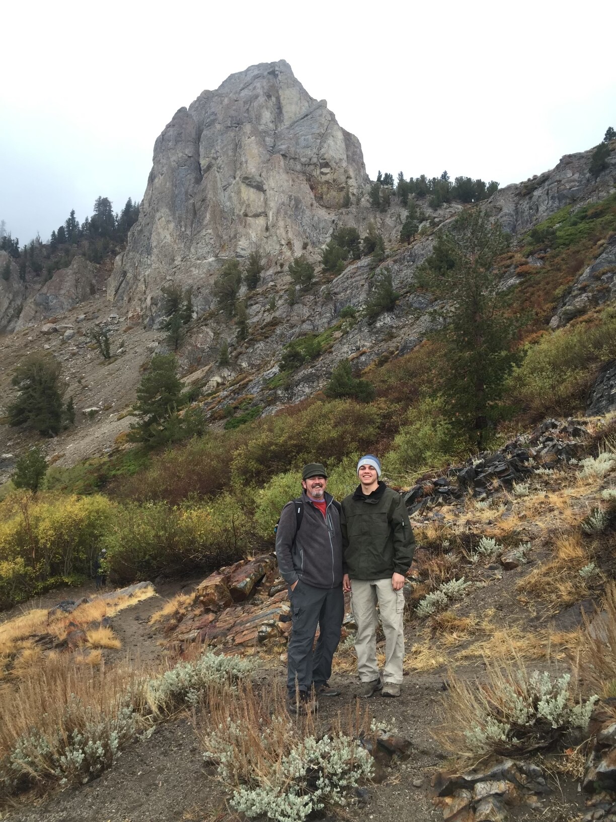 A younger and older man are hiking a mountain.