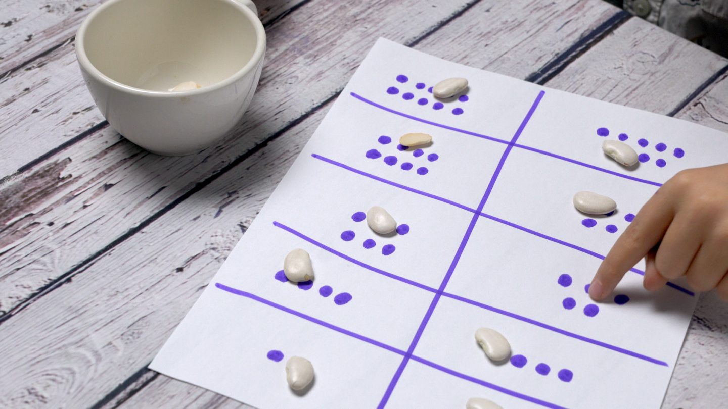 A small child counts out the dots on a sheet of paper divided in 10.
