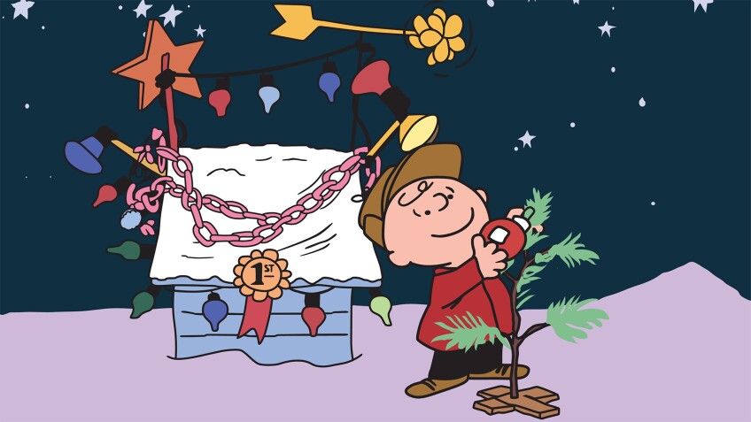 Charlie Brown decorates a tree next to Snoopy's Christmas-decorated doghouse. | "A Charlie Brown Christmas"