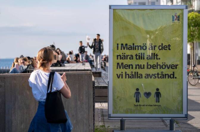 People enjoy the warm evening at Sundspromenaden as the sign reads "In Malmo everything is near. But now we need to keep a distance" in Malmo, Sweden May 26, 2020. TT News Agency/Johan Nilsson via REUTERS