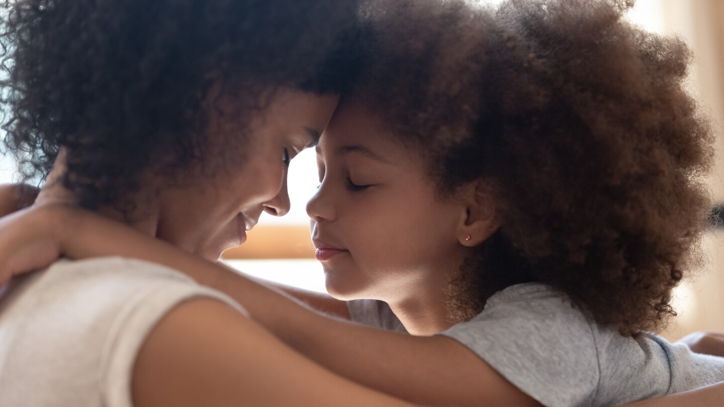 Mixed race mother touching foreheads with little cute daughter.