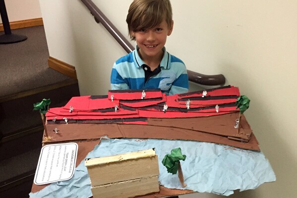 A student holds his group's prototype for an outdoor learning center and movie theater