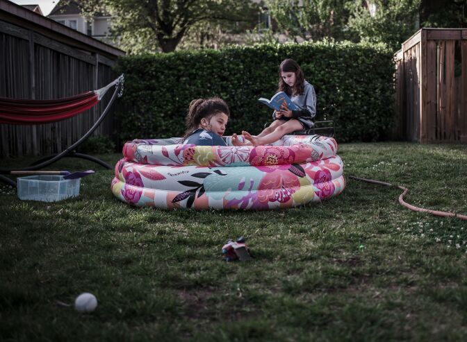 Two young girls playing in a small inflatable pool in the garden