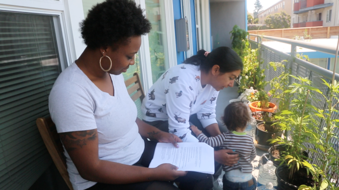Two women sit in a balcony with a child.