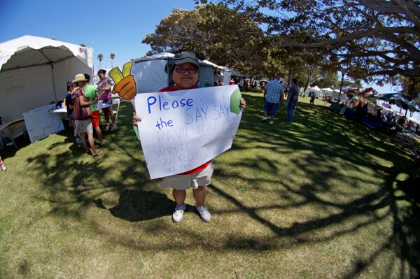 Festival worker roaming Pt. Fermin Park asking festival attendees to pass by the SaySay pavilion to contribute their stories