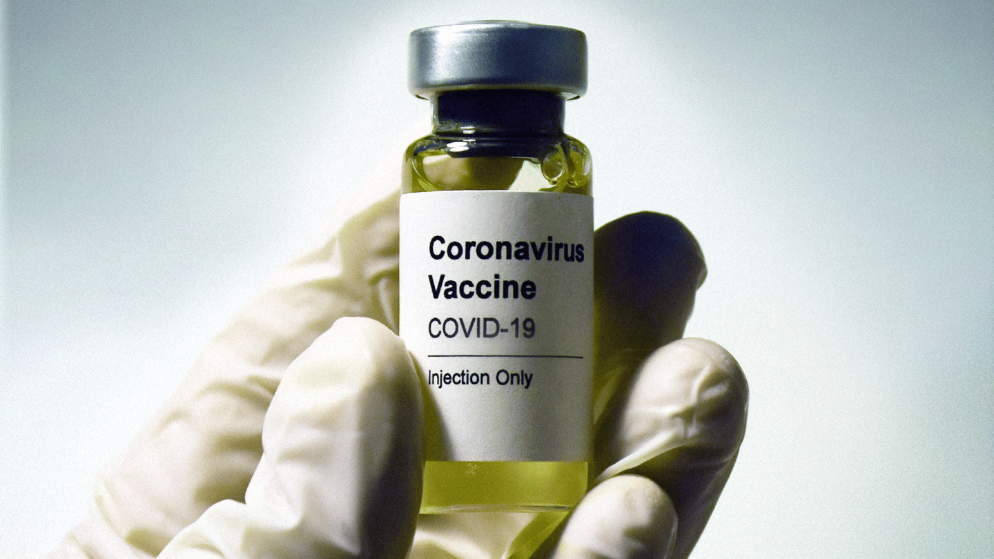 A coronavirus vaccine vial held in someone's hand.