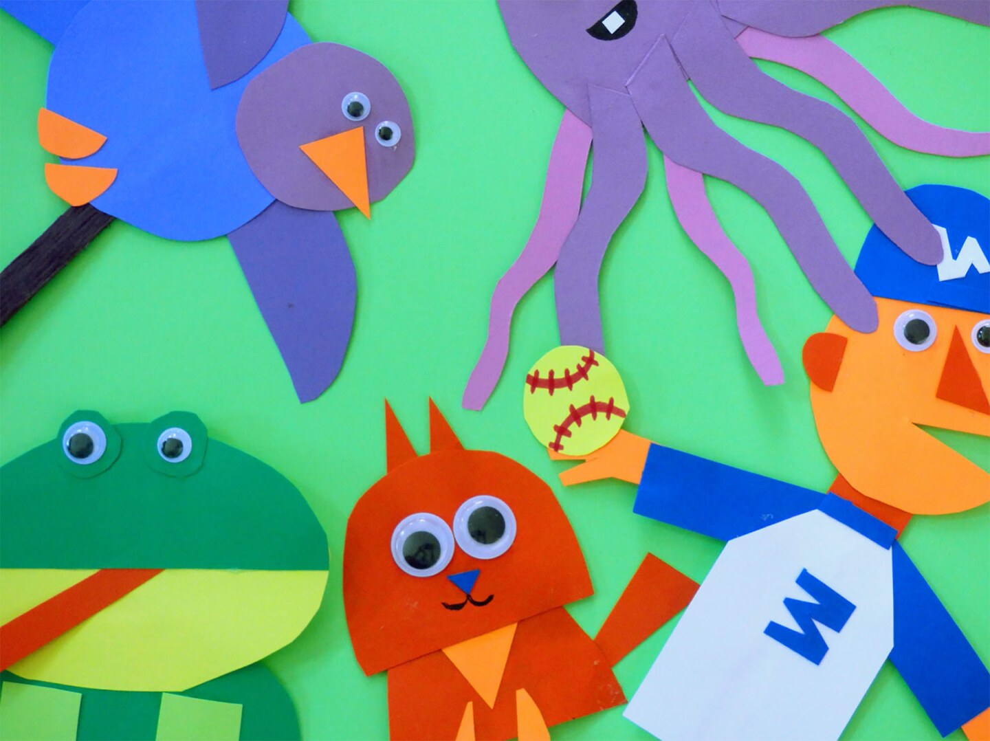 Varias marionetas de diferentes formas incluyendo un pájaro, pulpo, rana, gatito y jugador de béisbol sobre un fondo verde.