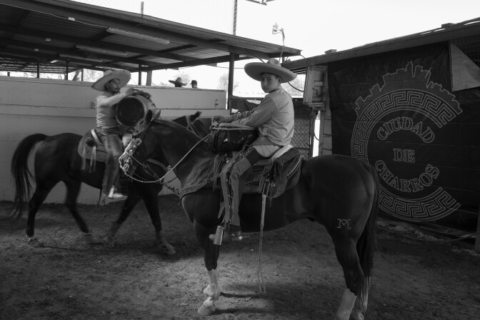 Jóvenes vestidos de charros montan a caballo con la frase Ciudad de Charros detrás.