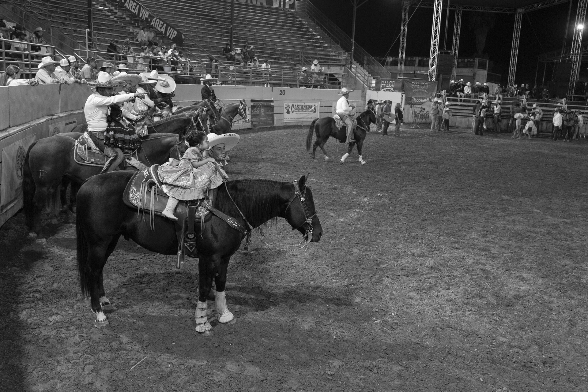 Niñas montando caballos junto a hombres adultos vestidos con ropa de rancho mexicano.