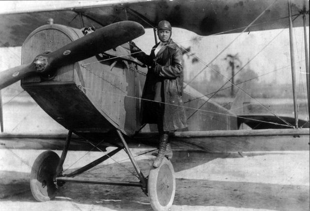 Bessie Coleman, shown here on the wheel of a Curtiss JN-4 “Jennie” in her custom-designed flying suit (circa 1924). | Smithsonian Institution