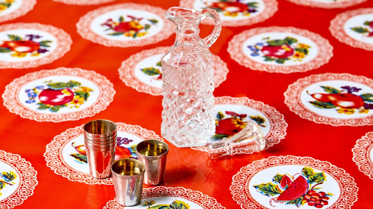 Clear vodka in a pitcher, pictured with metal cups.