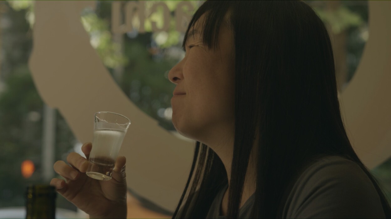Noriko Kamei enjoying sake | Still from "The Migrant Kitchen" Sequoia Sake