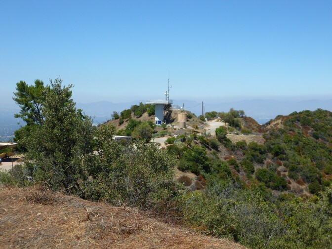 An observation tower sits at the top of a mountain. The foliage surrounding it is a bright green color.