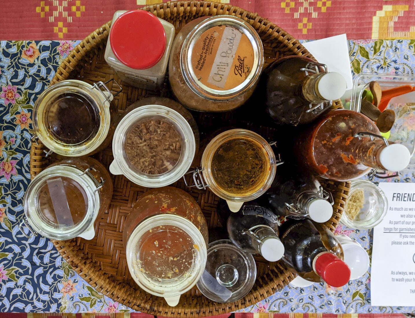 An overhead shot of a tray of spices and sauces used in or paired with Lao dishes. They are held in various glass jars and bottles.