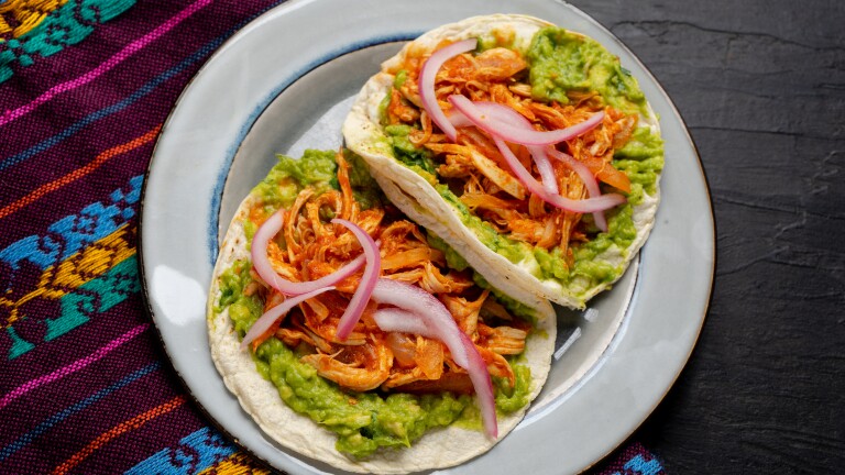 Chicken tacos with guacamole and onion on dark background