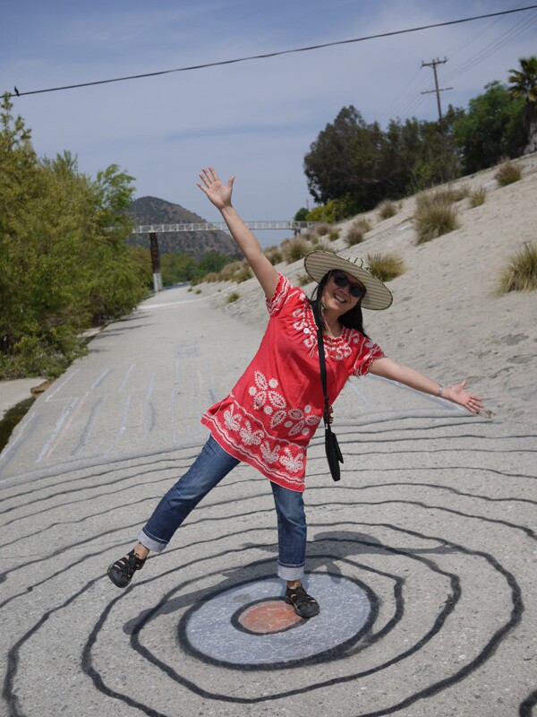 Atwater resident Angela Gee playfully poses on top of an artistic vortex creation along the riverbank | Photo by George Villanueva
