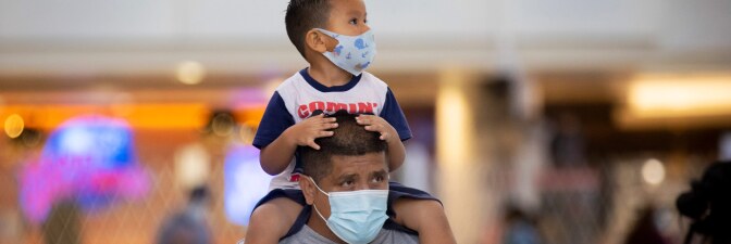 During the global coronavirus Mario Tejada walks with his son Mario Tejada, Jr. age 3, on his shoulders both wearing masks in Tom Bradley international at LAX on Tuesday, Nov. 17, 2020 in Los Angeles. | Francine Orr / Los Angeles