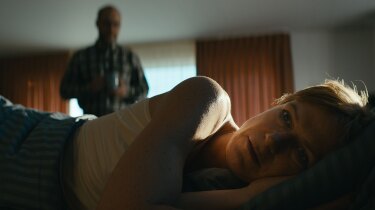 Anna lays in bed with her back against her husband. | Still from "Follow the Money" Season 3, Episode 5
