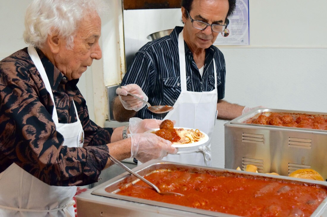 Volunteers serve meatballs and sausages for the feast, St. Joseph's Table