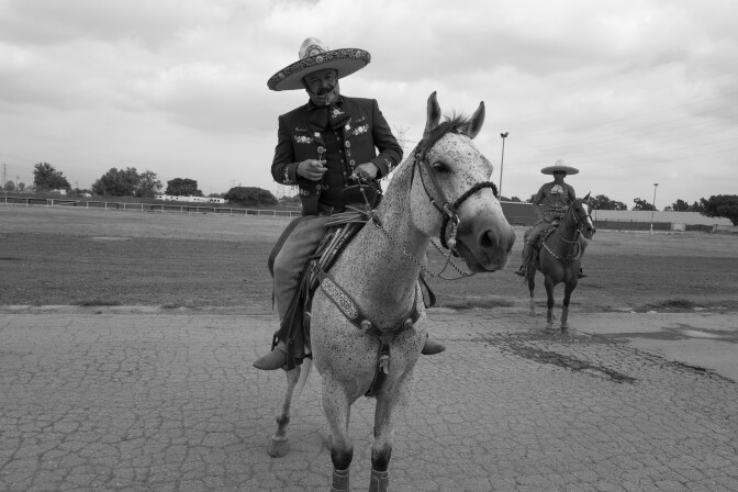 Sentado en el caballo de un hombre hay un traje completo de Sharida, que incluye una chaqueta bordada, pantalones a juego, chaparreras de cuero, un cinturón con diseños arabescos y un sombrero de fieltro de ala ancha.