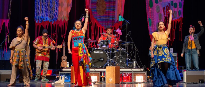 Dancers in a colorful wear with their fists up.
