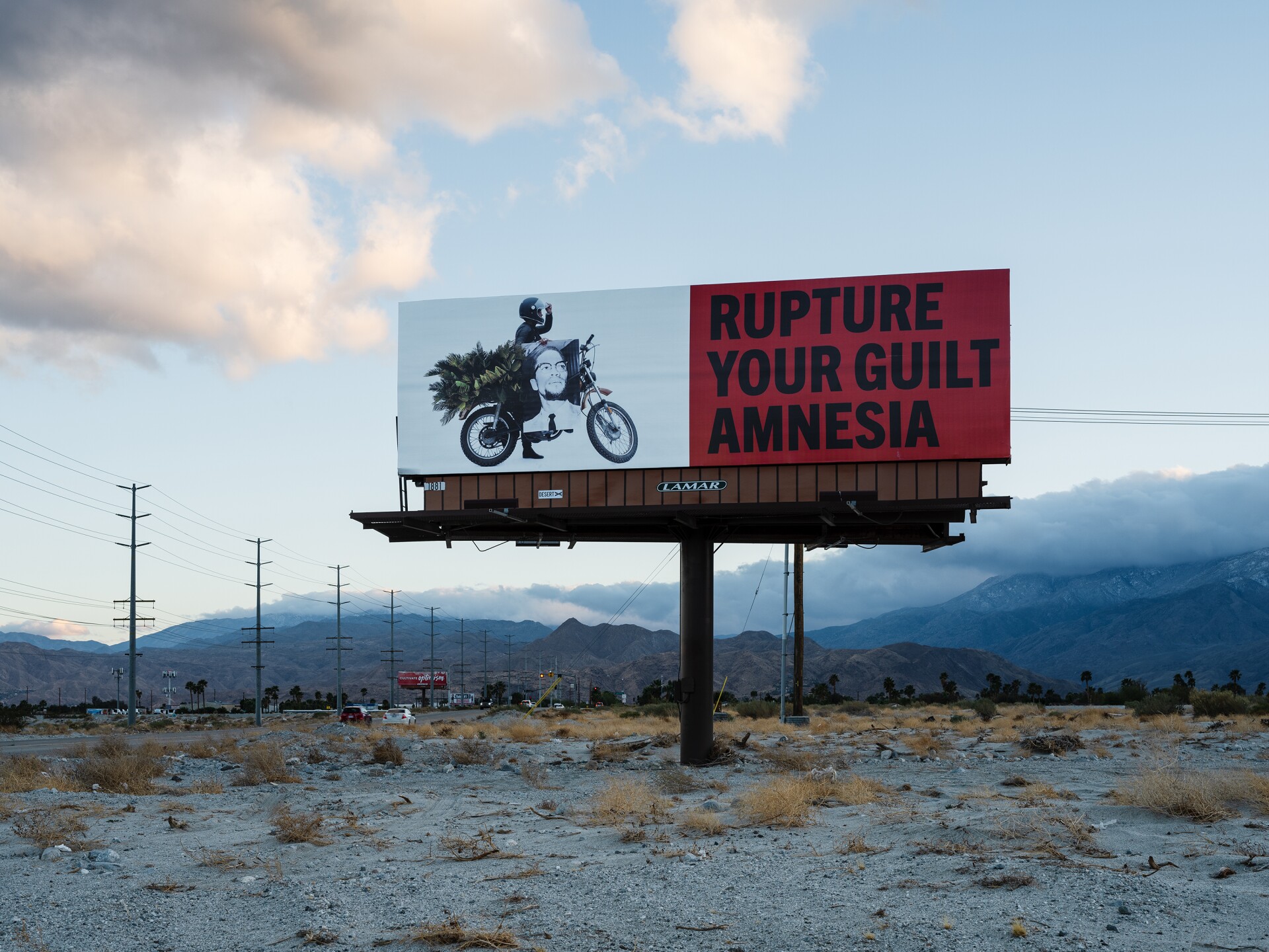 A billboard part of Simmons' art installation, "Because You Know Ultimately We Will Band a Militia," reads, "Rupture your guilt amnesia."
