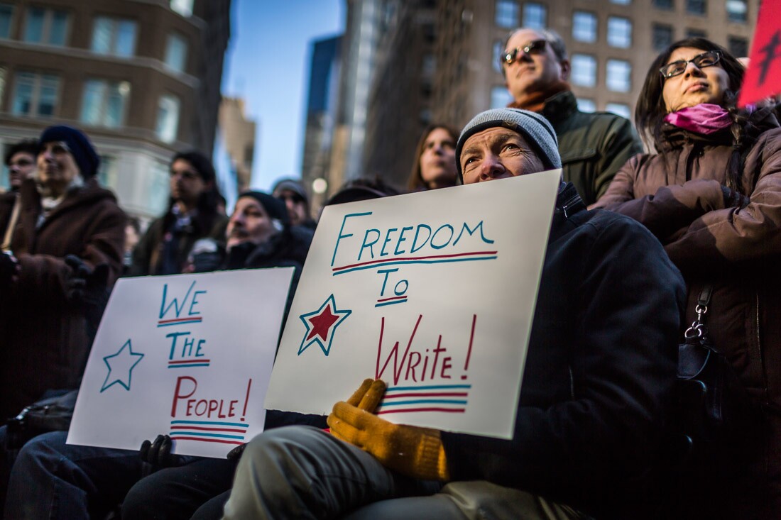 A protester holding a placard that writes ' Freedom to Write!'
