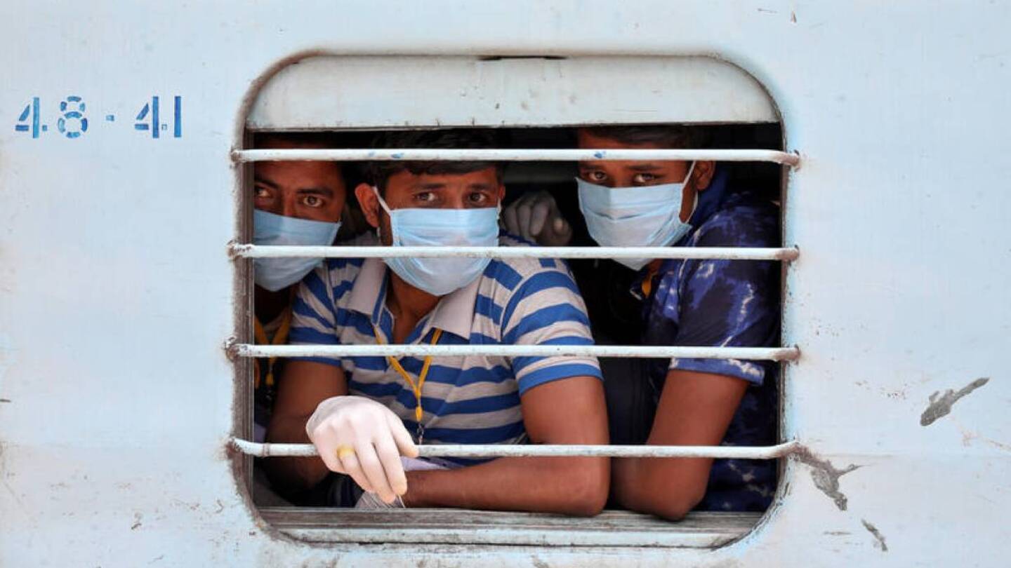 FILE PHOTO: Migrant workers, who were stranded in the western state of Rajasthan due to a lockdown imposed by the government to prevent the spread of coronavirus disease (COVID-19), wear protective masks as they look out from a window of a train