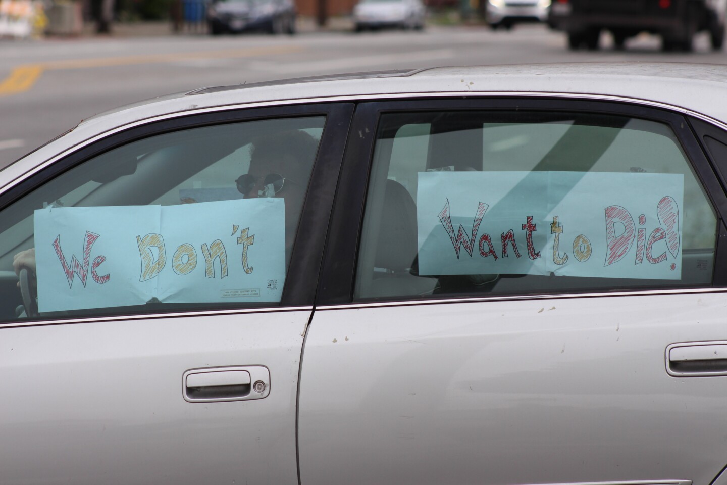 Signs reading "We don't want to die" taped to the inside of a car window, during protest at McDonalds on April 6, 2020 | Karen Foshay