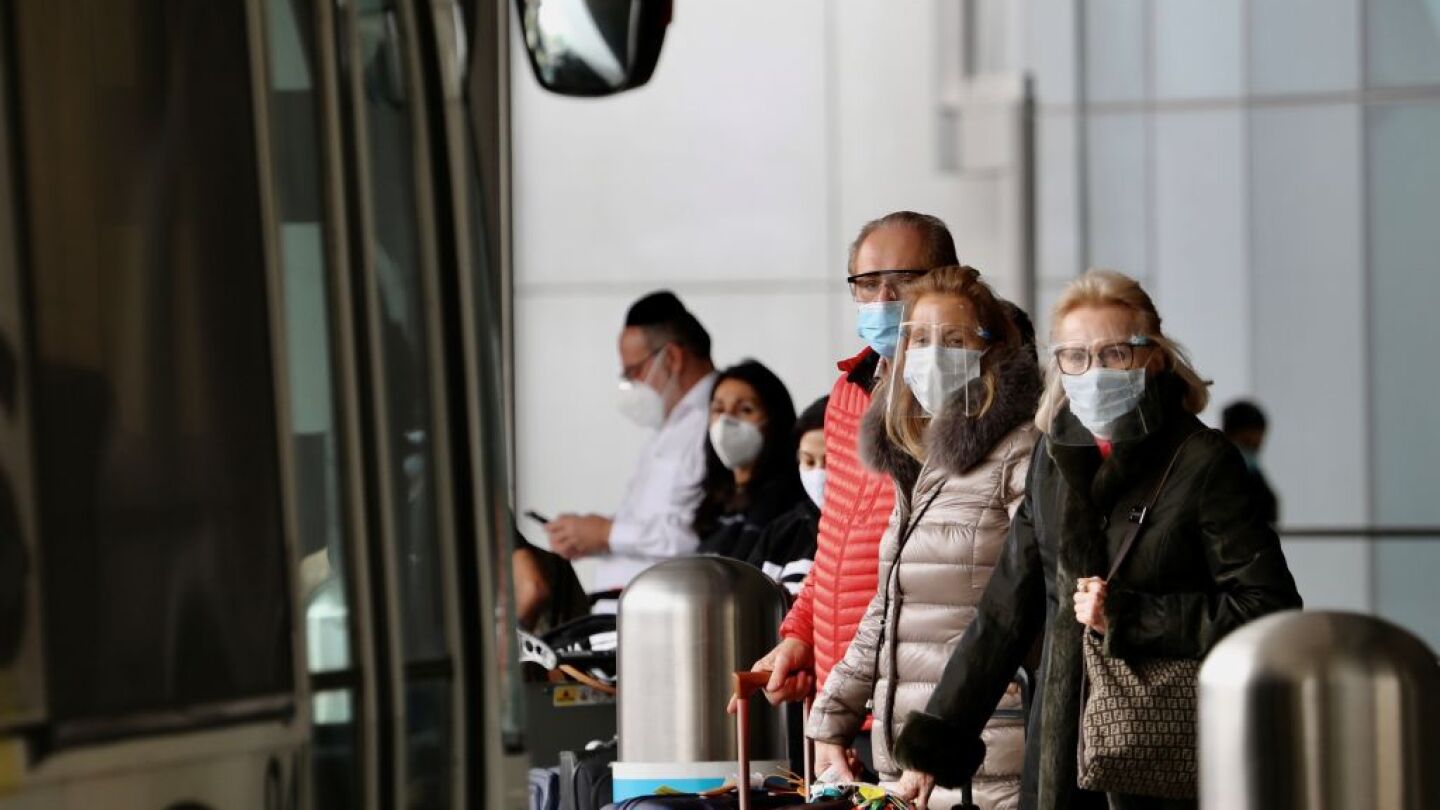 Travelers with face masks wait for public transportation services at the International Airport in Los Angeles, California, on Feb. 1, 2021.