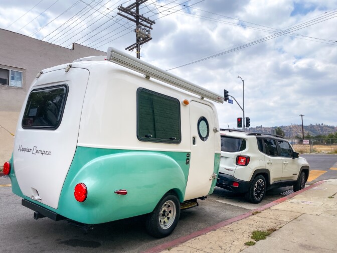 Pichardo's Mobile Art Lab, a teal and white trailer, is parked on the side of the road.