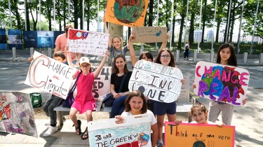A group of young climate activists hold up signs about climate change.