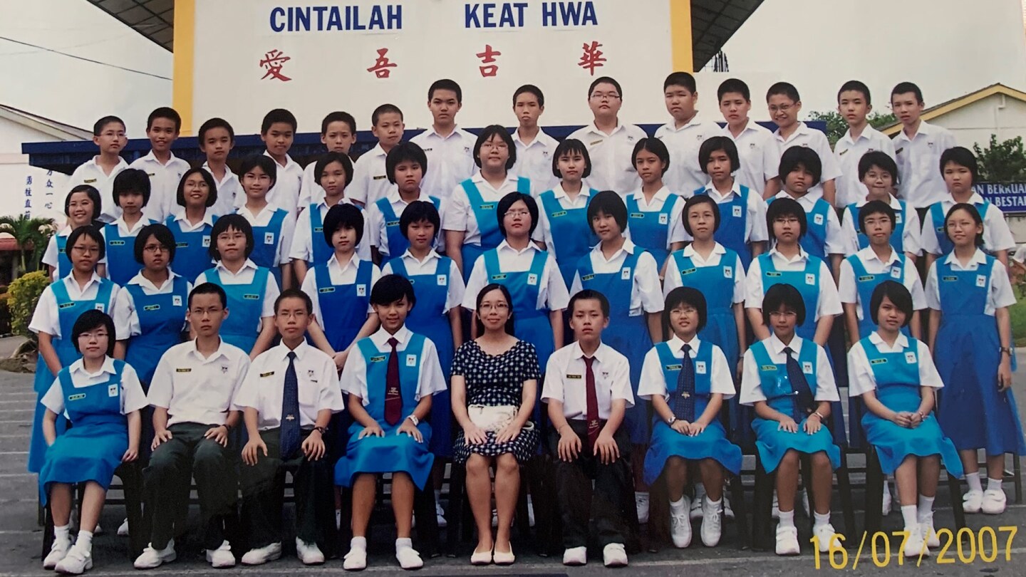 A group of young boys and girls in blue uniforms sit together facing the camera
