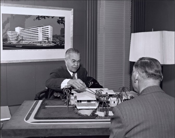 Paul R. Williams on the other side of the desk showing plans | J. Paul Getty Trust. Getty Research Institute, Los Angeles