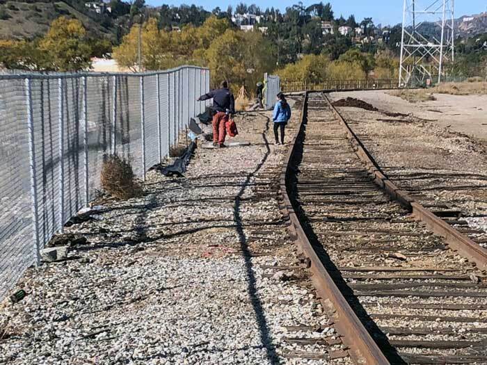 People walking between a fence separating the river from Taylor Yard. | Courtney Cecale