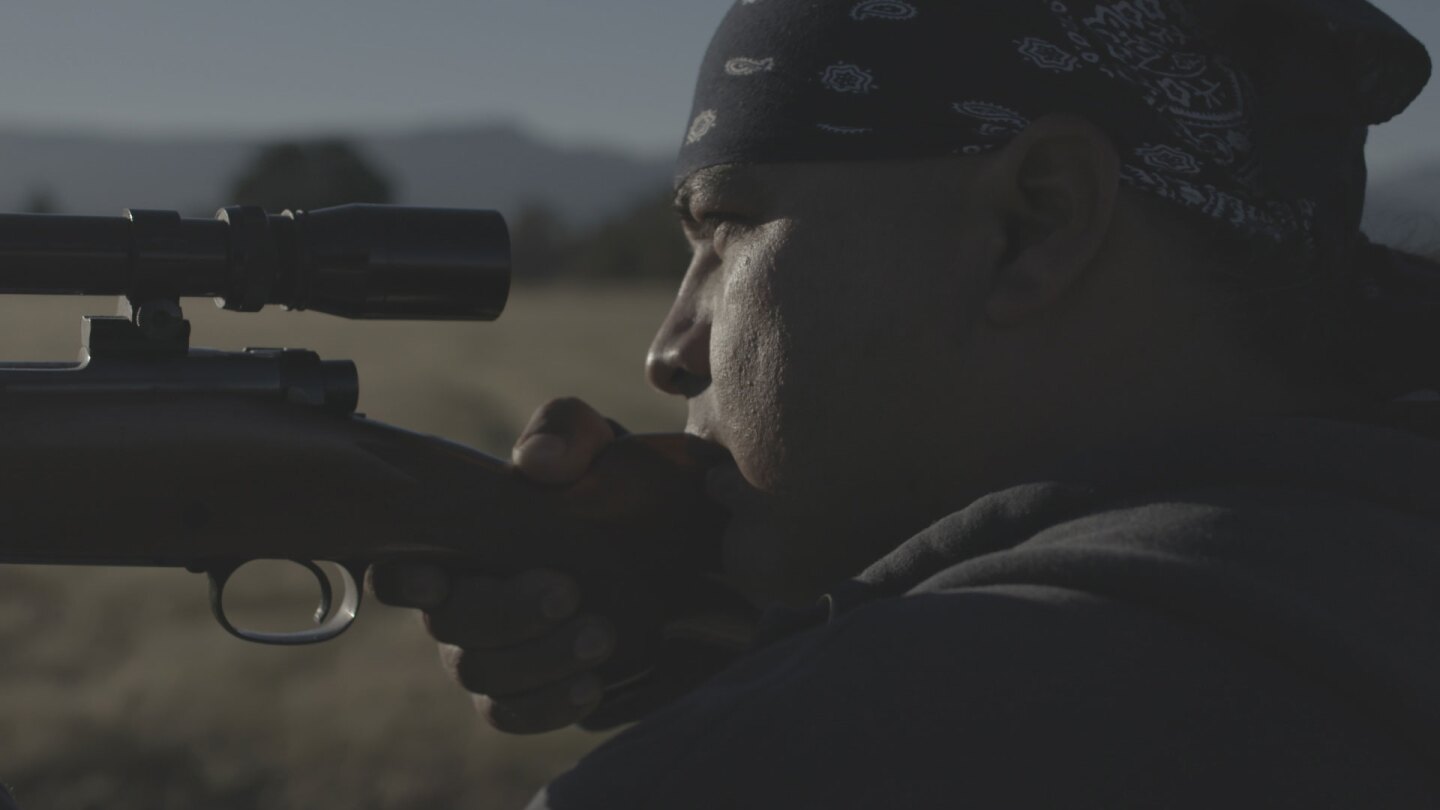Ray Alvarez looking into the iron sights of his rifle while hunting near the Pit River. | Still from "Tending Nature"