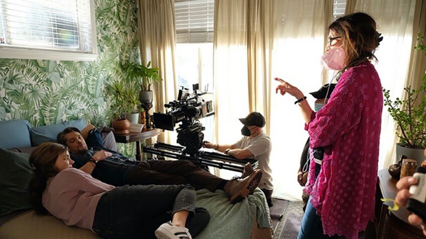 Director, crew and cast on a film set in a bedroom.