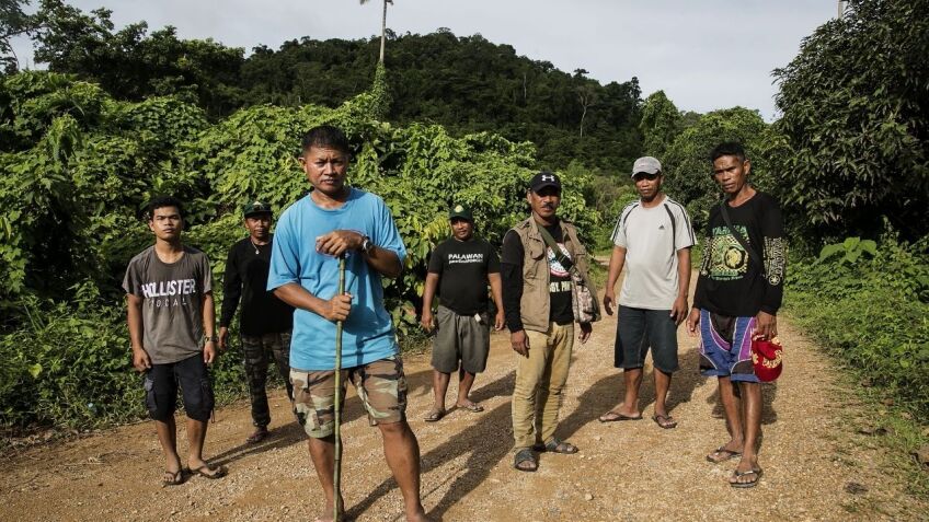 A group of people standing for the camera on a dirt road in a foresty area.