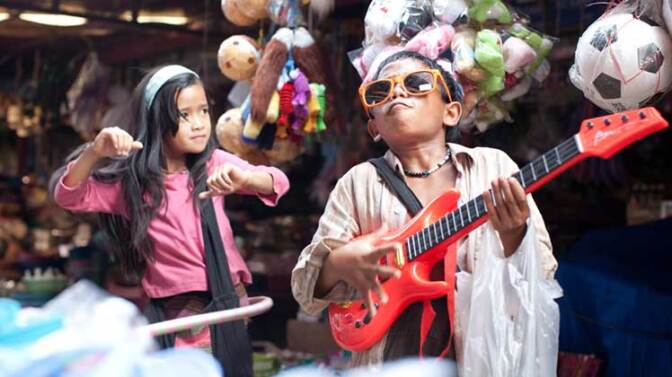 Two young children, including a boy holding a guitar who does James Brown impersonations. | Still from "Rocket"
