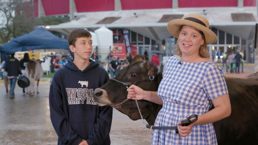 A woman holds onto the reins of a cow with a teenage boy next to her at the World Dairy Expo.