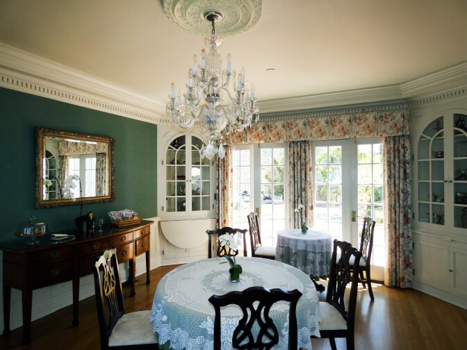 A formal dining room with a chandelier and patterned curtains.